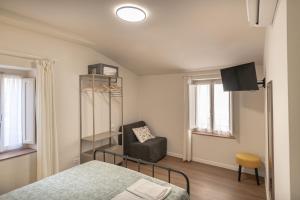 a bedroom with a bed and a chair and windows at Al Cantuccio Affittacamere in Assisi