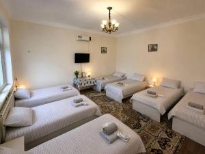 a living room with three beds and a tv at SAM GREEN HOUSE Hostel in Samarkand