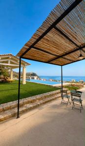 a picnic table and two chairs under a wooden canopy at Kalesma Himare in Himare