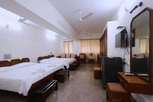 a hospital room with three beds and a television at YWCA International Centre in Mumbai