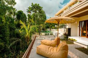 a patio with two chairs and an umbrella at Arcana Ubud in Ubud