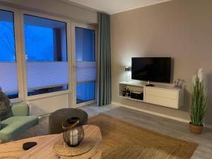 a living room with a television and a couch and a table at Ferienwohnung Sundkieker Fehmarn in Fehmarn