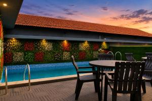 a patio with a table and chairs next to a pool at Hotel The Golden Sands, Located on Calangute Main Road in Calangute