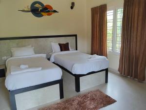 a bedroom with two beds with white sheets at Tutti Cafe in Hampi