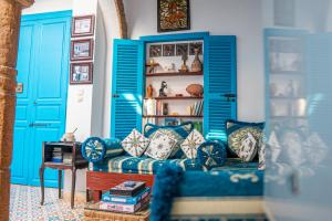 a living room with blue doors and a couch with pillows at Riad Le Cheval Blanc in Safi