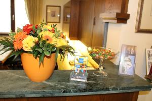 an orange vase with flowers on top of a counter at Hotel Alte Post in Krefeld