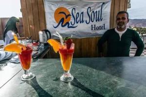 a man standing at a table with two cocktails at Sea Soul Hotel in Dahab