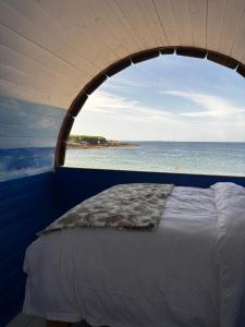 a bedroom with a window with a view of the beach at Glamping Pod in Milltown Malbay