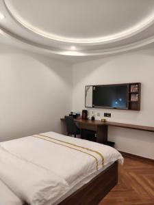 a bedroom with a bed and a desk with a flat screen tv at Furaton Hotel in Ðức Hòa