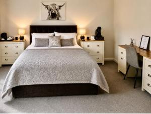 a bedroom with a large bed with a desk and a desk at Eldon Lea in Strathpeffer