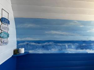 a blue and white wall with a painting of the ocean at Glamping Pod in Milltown Malbay +3 photos