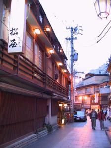 a street with people walking down a street with buildings at Senshinkan Matsuya in Yamanouchi