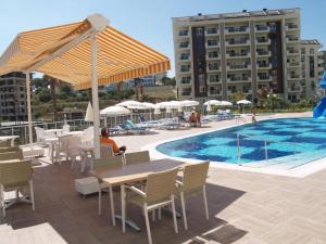 uma pessoa sentada numa mesa ao lado de uma piscina em Orion Resort Gülay 18 em Avsallar