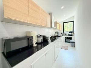 a kitchen with white cabinets and a black microwave at Nook Villa in Ban Khlong Mae Nam