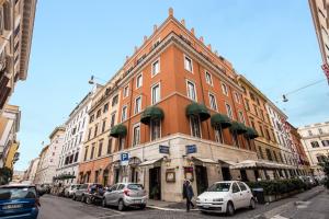 un gran edificio de ladrillo en una calle de la ciudad con coches aparcados en Hotel Tito, en Roma