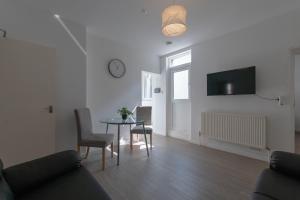 a living room with a table and a clock on the wall at Edinburgh Shore Apartments in Edinburgh