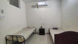 a room with two beds and a nightstand and a room with at Radhe Krishna Guest House in Srīrangam