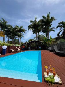 a swimming pool with drinks on a wooden deck at Gite d'Arles "Villa Doudou" in Le Moule