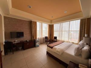 a bedroom with a bed and a desk and a television at Royal Grand Hotel in Monrovia