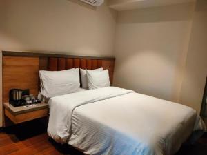 a bedroom with a large bed with white sheets and pillows at Ayushmaan Hotel - near Jabalpur Railway Station in Jabalpur