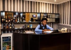 a woman sitting at a counter in a bar at Aneks Ibro Hotel, Wuse Zone 5, Abuja in Abuja