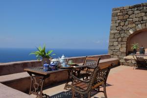 a table and chairs on a patio with the ocean at Dammuso Il Sogno in Scauri