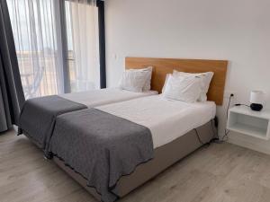 a bedroom with a large bed with a large window at Apartamento T1 - MedSal Residence in Santa Maria