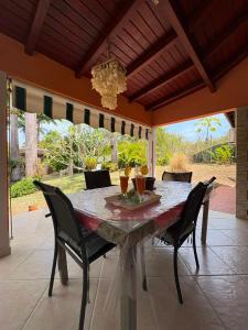 a dining room table with chairs and a chandelier at Gite d'arles Bungalow "La Rose" in Le Moule