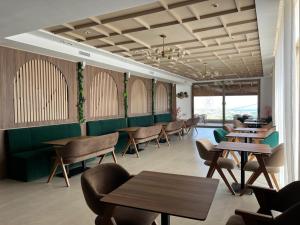 a restaurant with wooden tables and chairs and green booths at Dar Zaha in Aguenouane