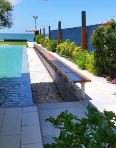 a bench next to a pool with the ocean in the background at Baan Thew Talay Blue Sapphire in Cha Am