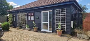 a black house with potted plants in front of it at Blackberry Cottage, Wood Farm in Shipdham
