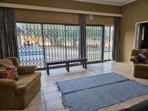 a living room with a couch and a large window at Tambuki Backpackers & Self-catering - Dinokeng in Hammanskraal
