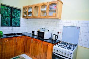 a kitchen with a stove and a microwave at Paki hotels moshi in Msaranga