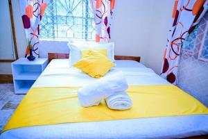 a yellow and white bed with towels on it at Paki hotels moshi in Msaranga