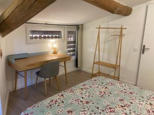 a bedroom with a desk and a bed with a chair at Gîte de Lafeuillade in Montech