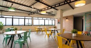a cafeteria with tables and chairs and windows at Hotel Vijaya Suites in Manipal
