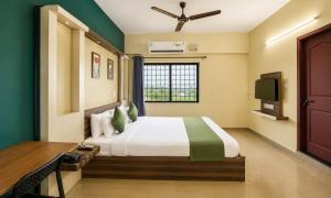 a bedroom with a bed and a desk and a television at Hotel Vijaya Suites in Manipal