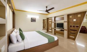 a bedroom with a bed and a television in it at Hotel Vijaya Suites in Manipal