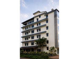 a white building with a palm tree in front of it at Hotel Vijaya Suites in Manipal