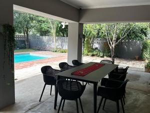 a table and chairs in a patio with a pool at Dessert Rose Guesthouse in Jwaneng