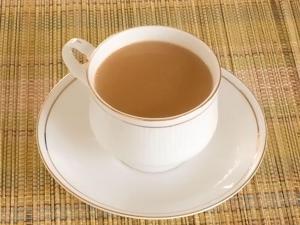 a cup of coffee on a plate on a table at Ayushmaan Hotel - near Jabalpur Railway Station in Jabalpur