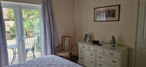 a bedroom with a bed and a dresser and a window at Blackberry Cottage, Wood Farm in Shipdham