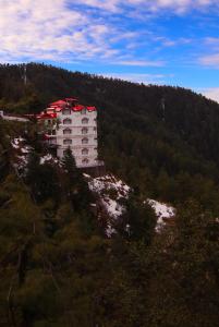 a building on the side of a hill with trees at Kufri Pacific Resort in Mundaghat 