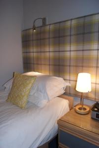 a bedroom with a bed and a table with a lamp at Shegarton Farm Cottages in Luss