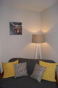 a living room with a gray couch with yellow pillows at Shegarton Farm Cottages in Luss