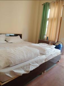 a bedroom with a bed with white sheets and a window at Gyatso Home Saty in Kaza +5 photos