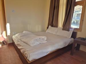 a unmade bed in a room with a window at Gyatso Home Saty in Kaza
