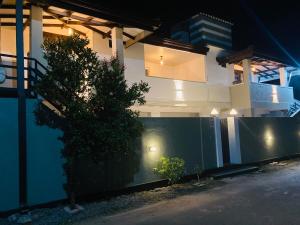 a house with a tree in front of a fence at My Place Sri Lanka CMB Near Airport in Katunayaka
