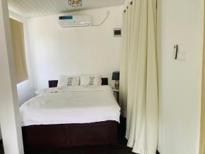 a bedroom with a white bed and a curtain at My Place Sri Lanka CMB Near Airport in Katunayaka +16 photos
