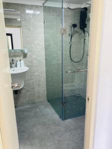 a shower with a glass door next to a sink at My Place Sri Lanka CMB Near Airport in Katunayaka